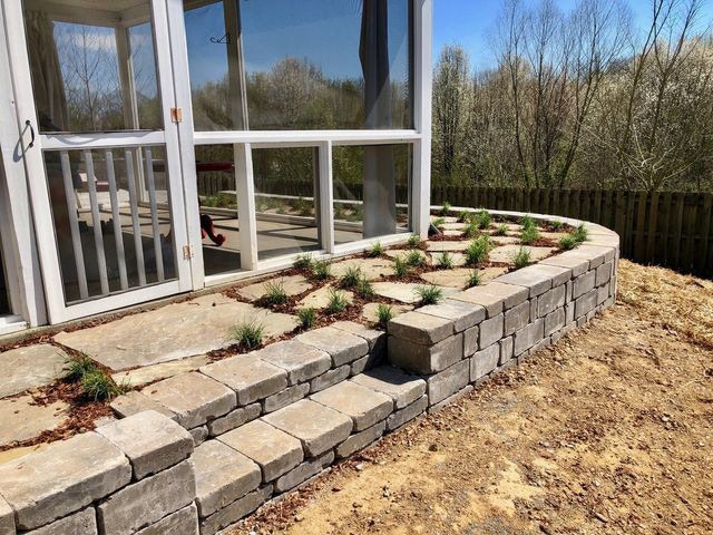 A screened in porch with a stone wall and steps leading to it.