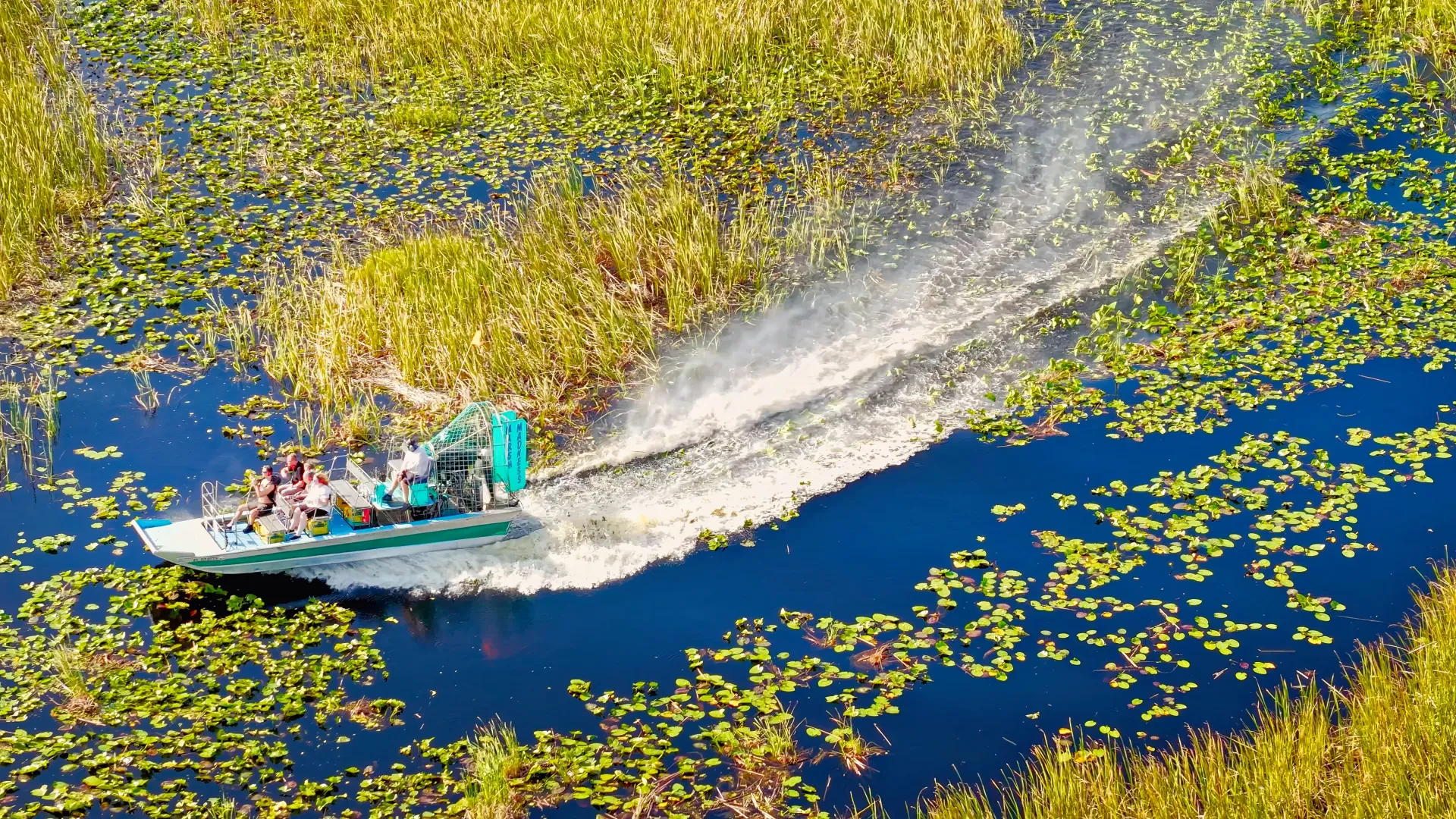 Airboat speeding through the Everglades wetlands during Miami Everglades tours aerial view