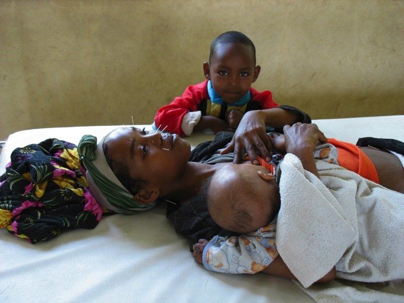 A woman is laying on a bed holding a baby