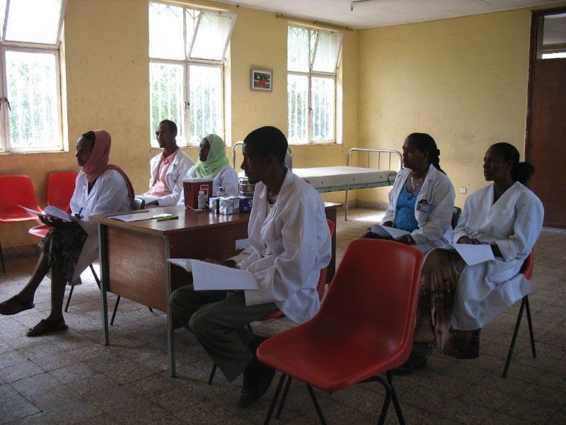 A group of people in white coats are sitting in a room