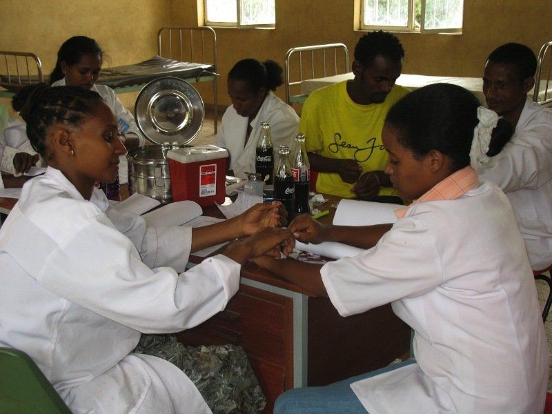 A woman in a yellow shirt is sitting at a table with other women