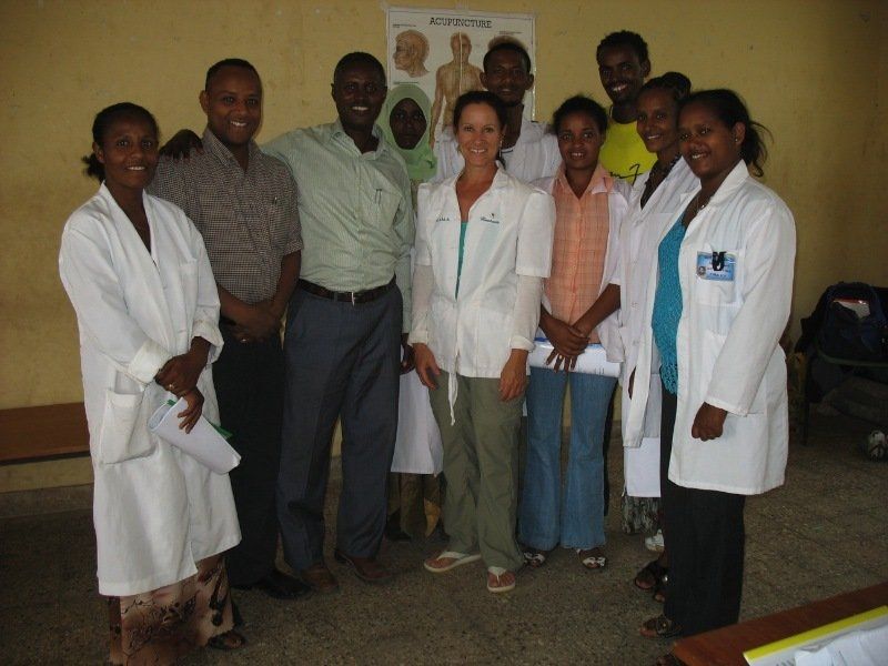 A group of people posing for a picture with one woman wearing a name tag