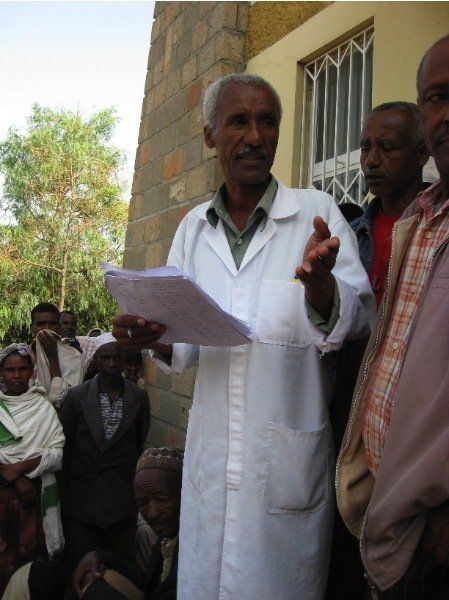 A man in a white coat is holding a piece of paper