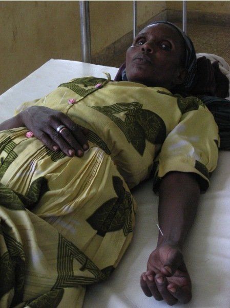 A woman in a yellow dress is laying in a hospital bed