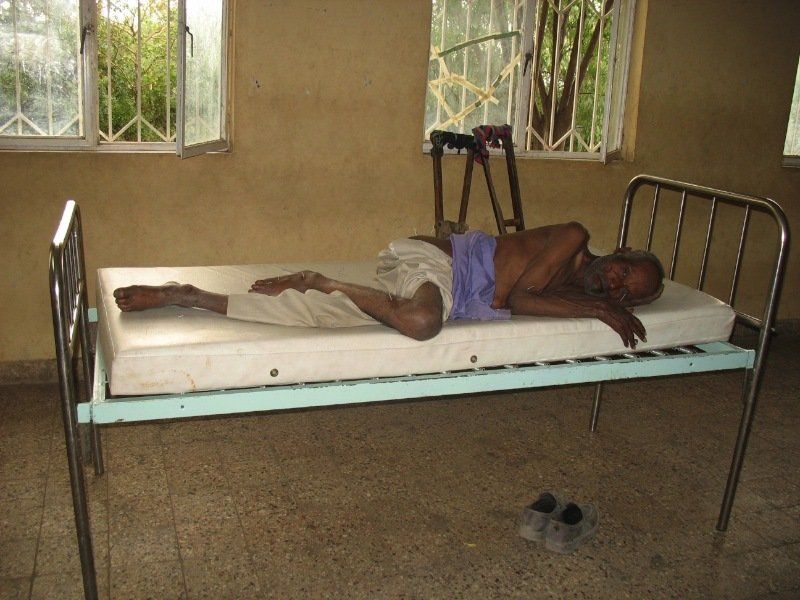 A man is laying on a bed with his legs crossed