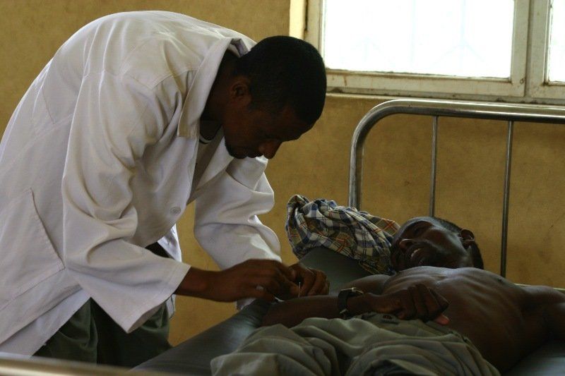A doctor examines a patient 's arm in a hospital bed