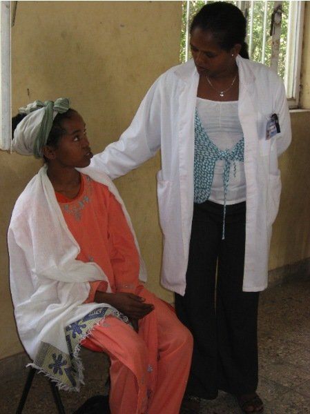 A woman in a white coat talks to another woman