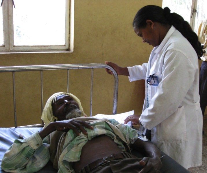 A woman in a white coat is measuring a man in a hospital bed