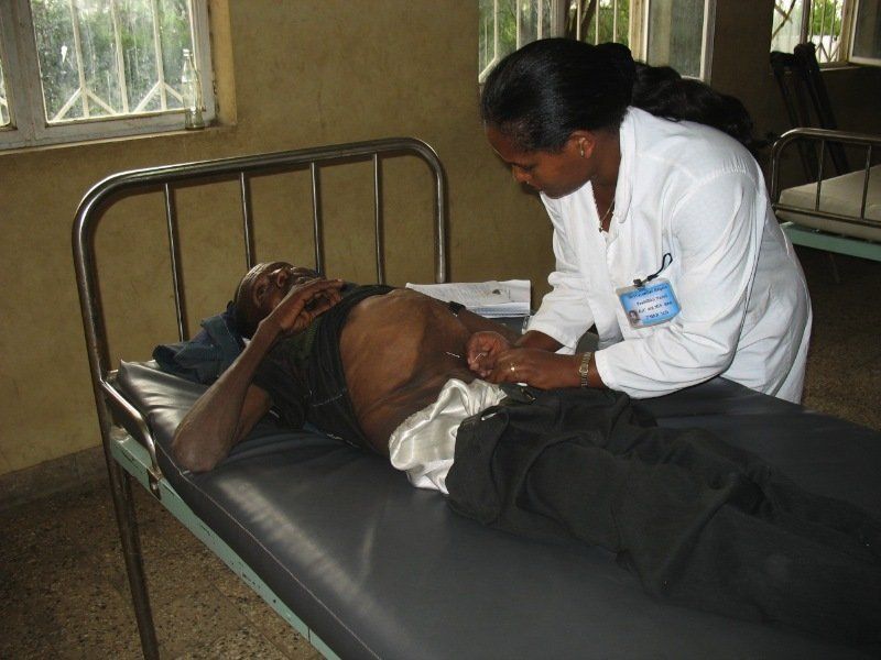 A doctor is examining a patient 's stomach in a hospital bed