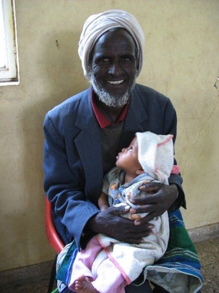 A man with a beard is holding a baby in his arms