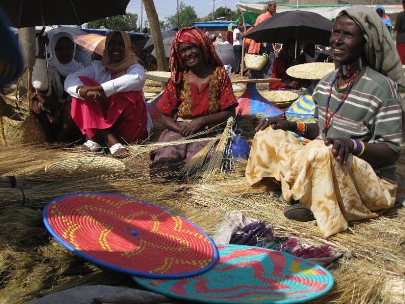 A group of women are sitting on the ground with a broom and umbrellas