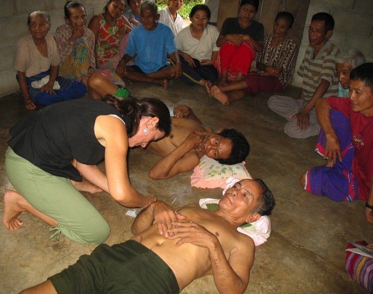 A group of people are sitting around a man laying on the floor