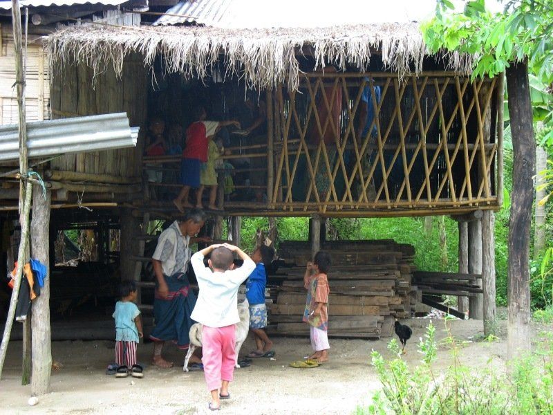 A group of people standing outside of a thatched hut
