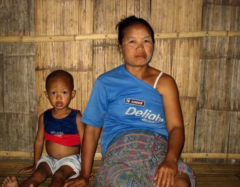 A woman wearing a blue delilah shirt sits next to a child