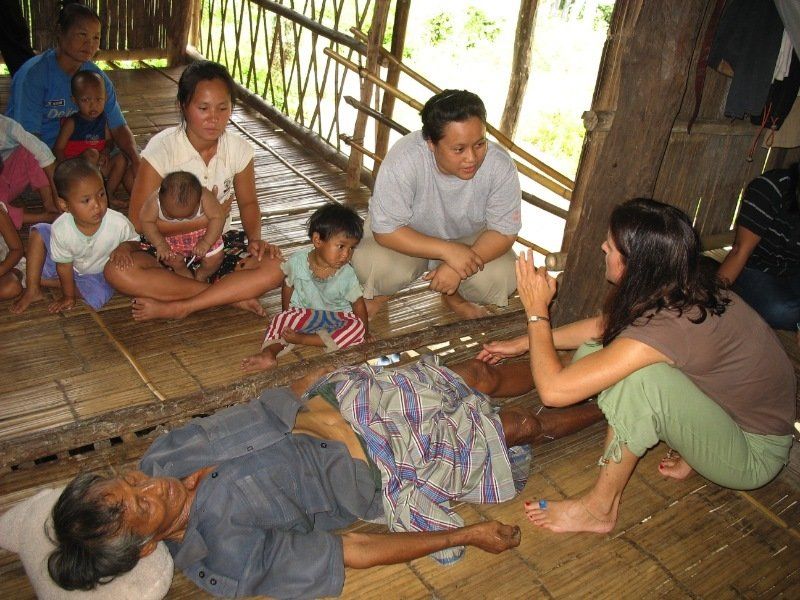 A group of people are sitting around a man laying on the floor