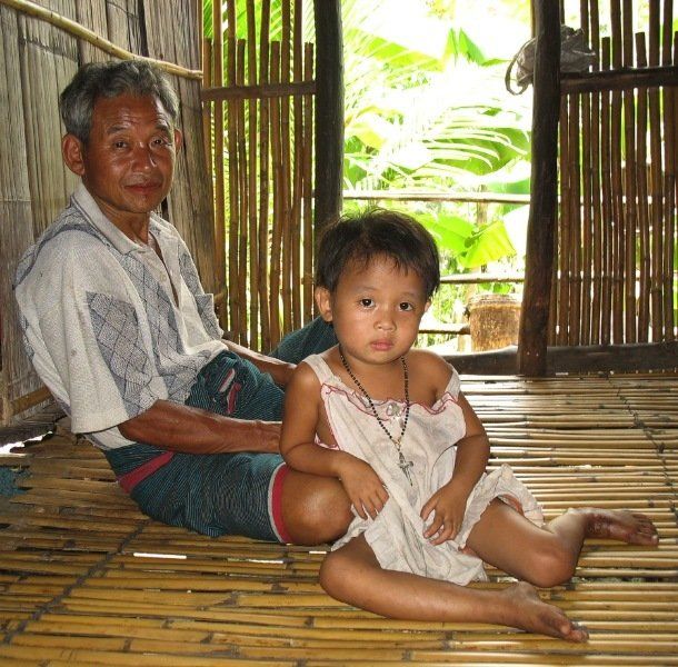 A man and a little girl are sitting on a bamboo floor