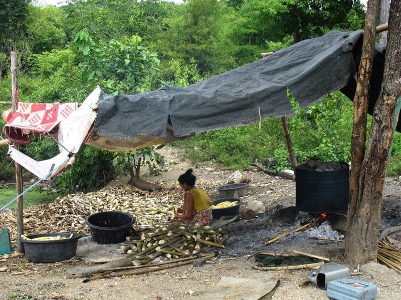 A woman is sitting under a tarp in the dirt