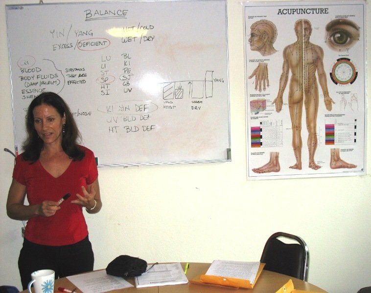 A woman stands in front of a whiteboard that says balance