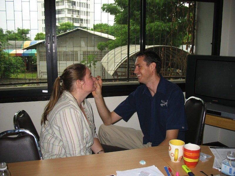 A man is touching a woman 's face while sitting at a table in front of a window
