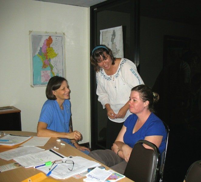 Three women are sitting around a table with papers on it
