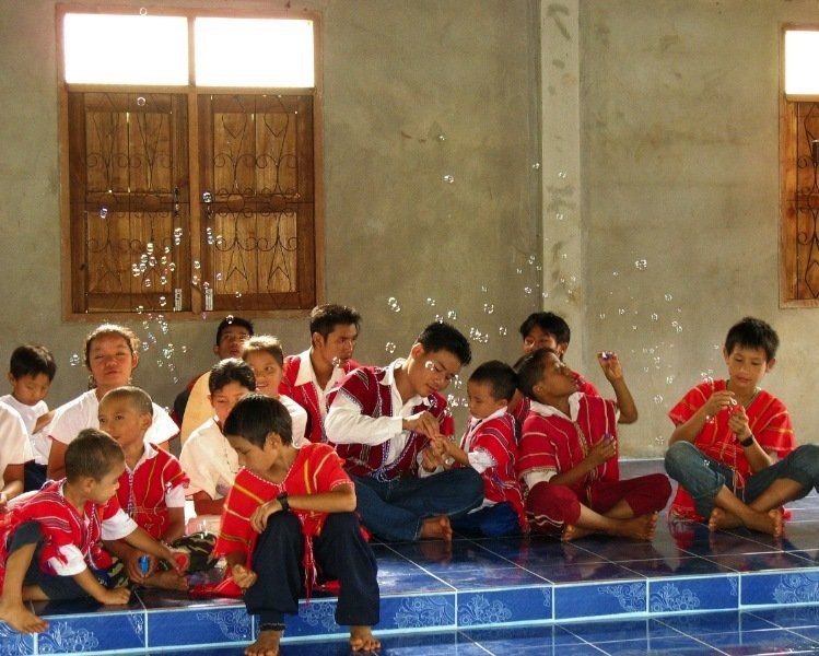 A group of children are sitting on the floor playing with soap bubbles