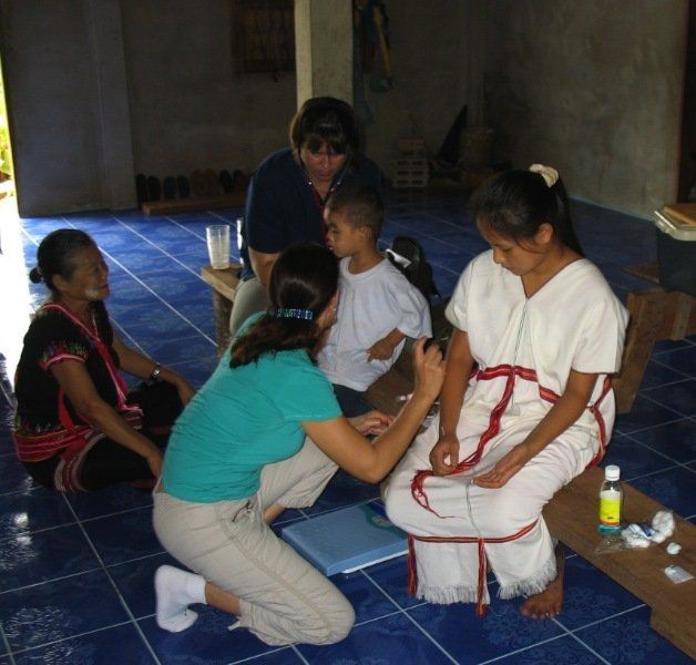 A woman in a blue shirt is kneeling down to help a child