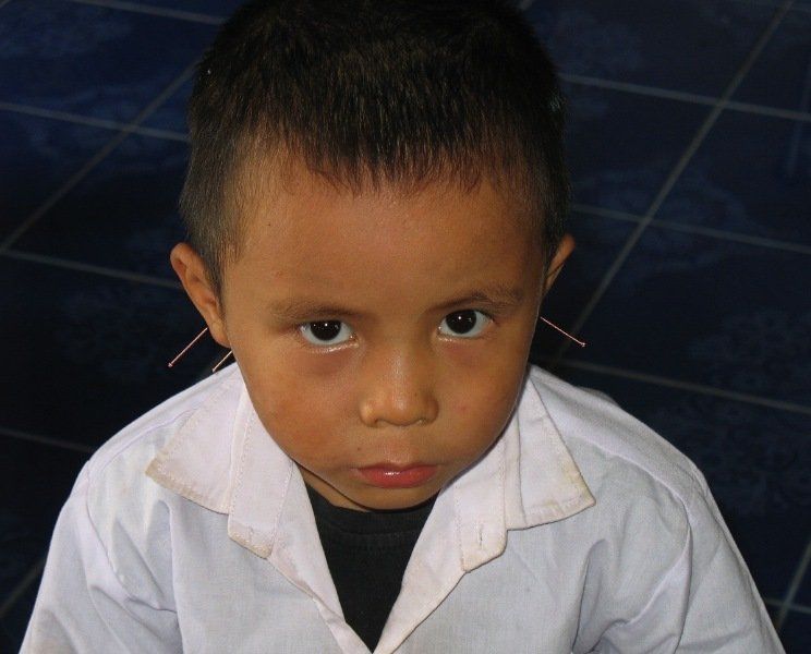 A young boy wearing a white lab coat looks at the camera