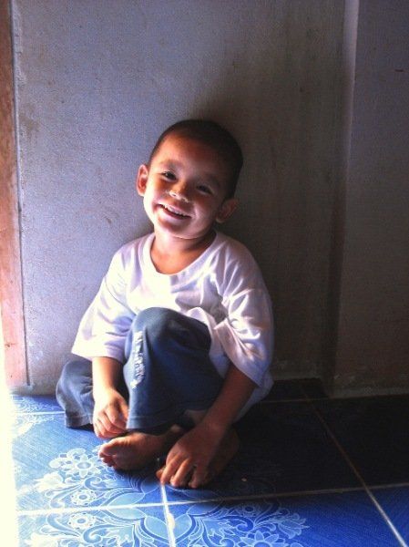 A little boy is sitting on the floor and smiling