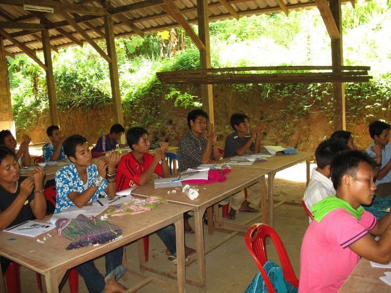 A group of children are sitting at tables in a classroom