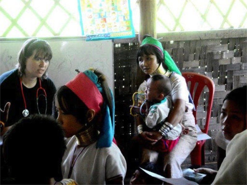 A woman with a stethoscope around her neck is holding a baby