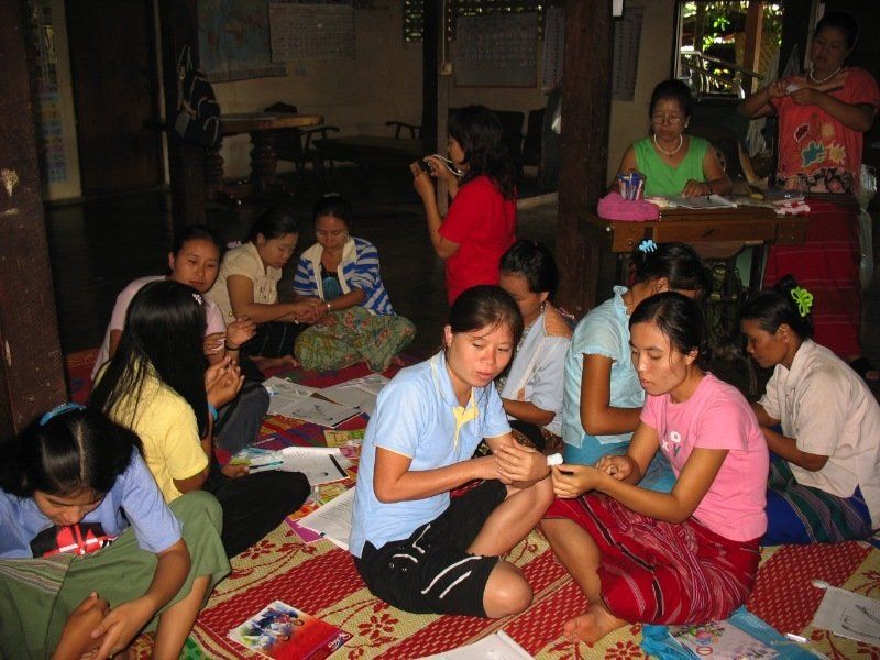 A group of women are sitting on the floor working on crafts