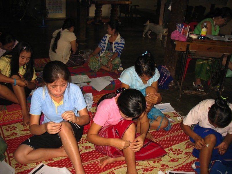 A group of young girls are sitting on the floor in a classroom