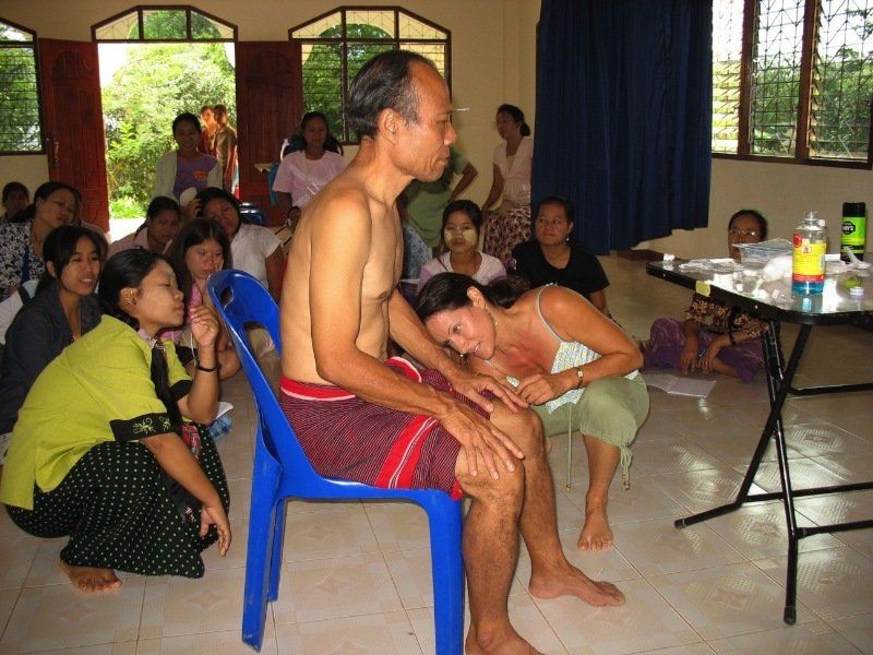 A group of people are sitting around a table with a man sitting in a blue chair