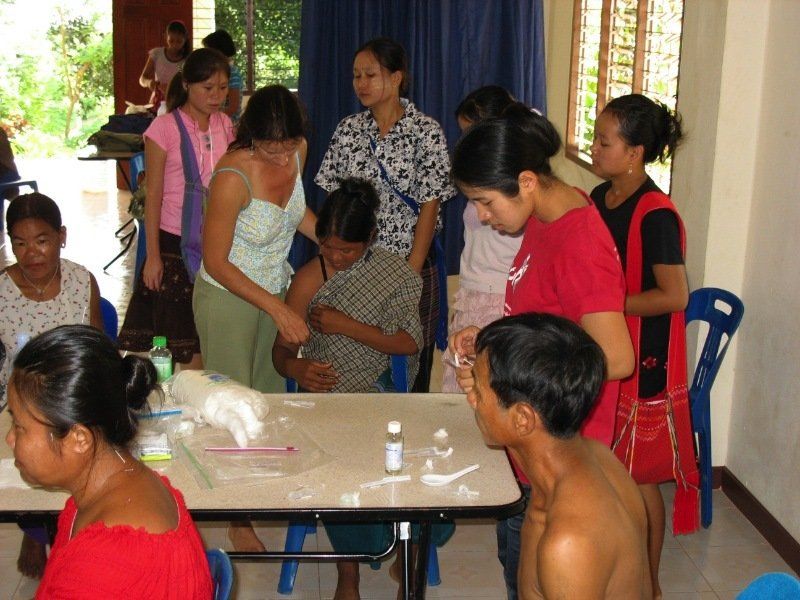 A group of people are gathered around a table including a shirtless man