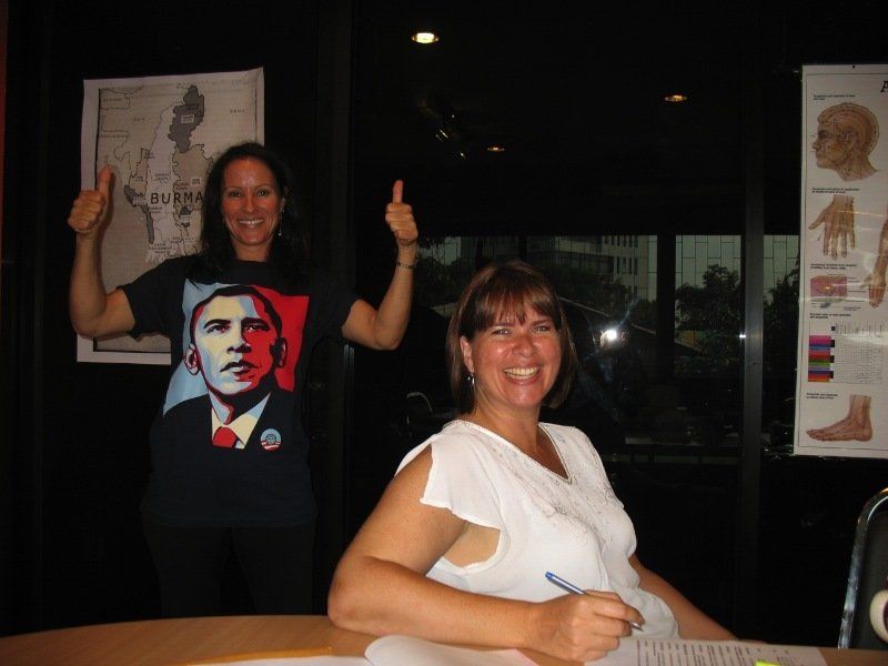 Two women are posing for a picture with one wearing a barack obama shirt