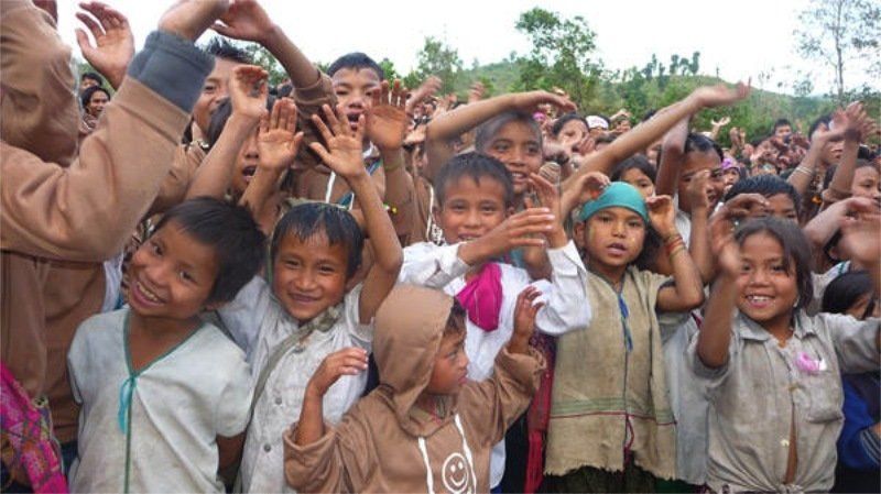 A group of children are posing for a picture with their hands in the air.