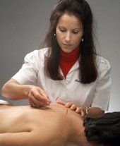 A woman is giving an acupuncture treatment to a patient.
