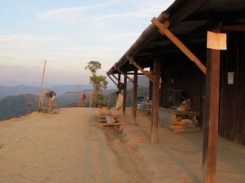 A wooden building with a covered porch on top of a hill