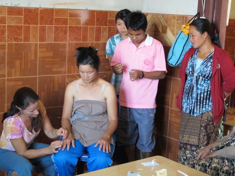 A group of people are gathered around a woman sitting at a table