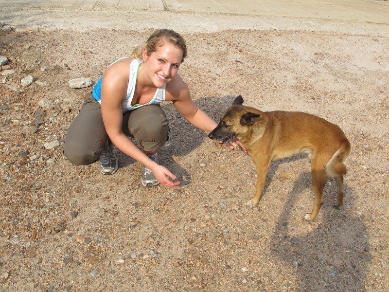 A woman kneeling down next to a brown dog