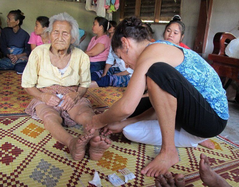 A woman is putting a bandage on an older woman 's foot