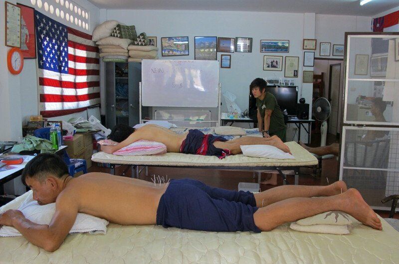 A man and a woman are laying on a bed in a room with an american flag on the wall.