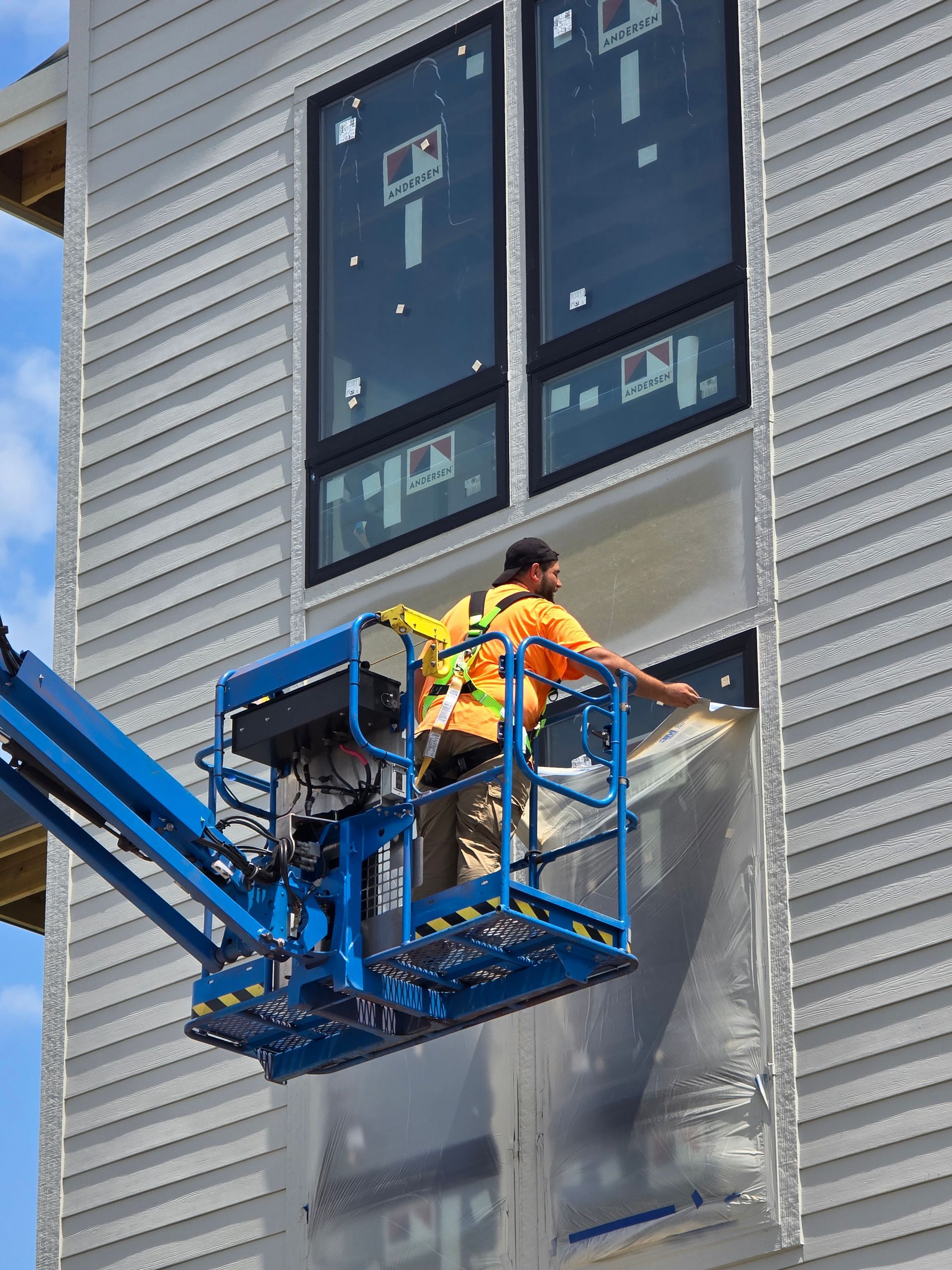 A man is working on a building from a crane.