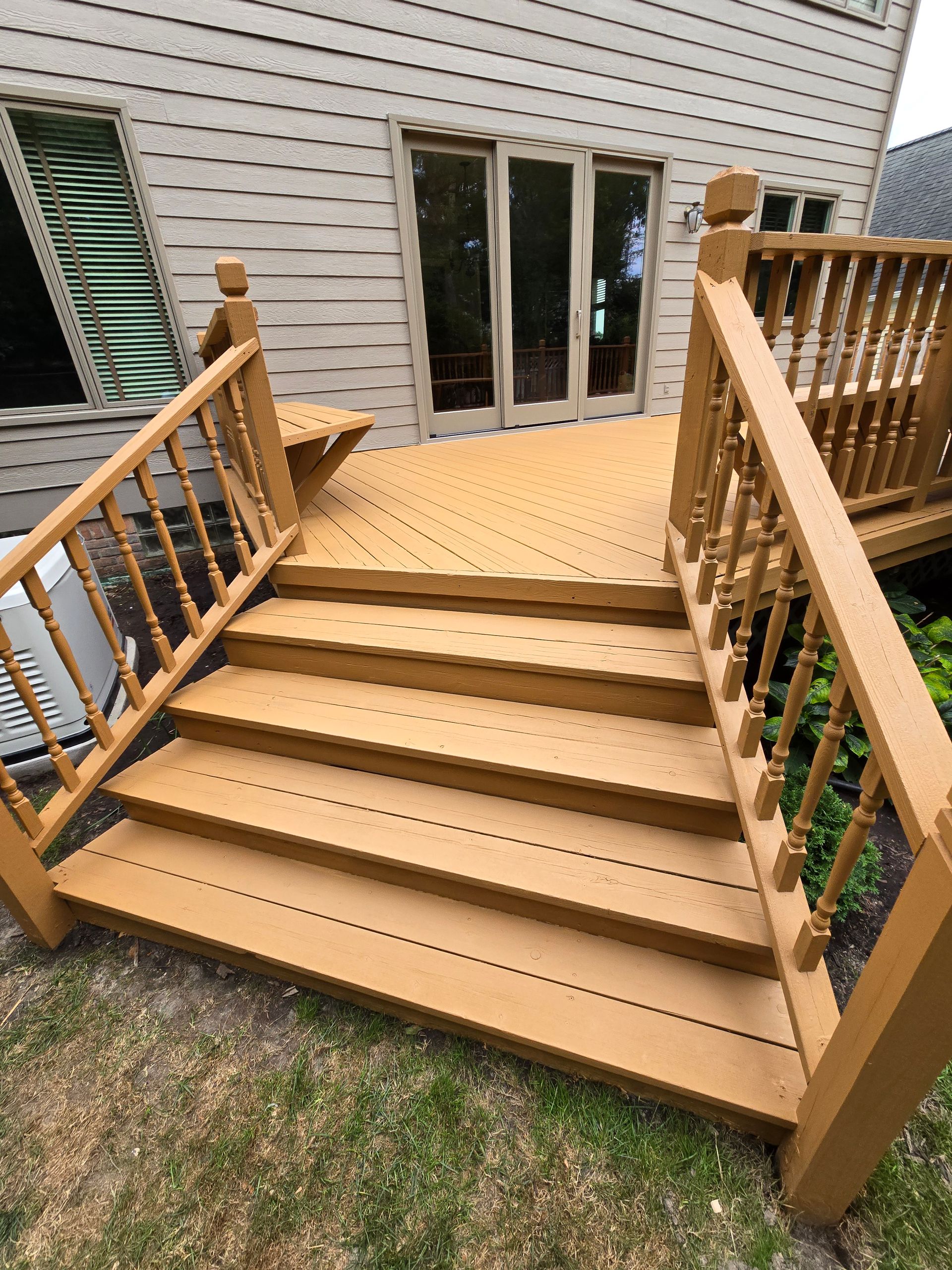 A wooden deck with stairs and a railing in front of a house.