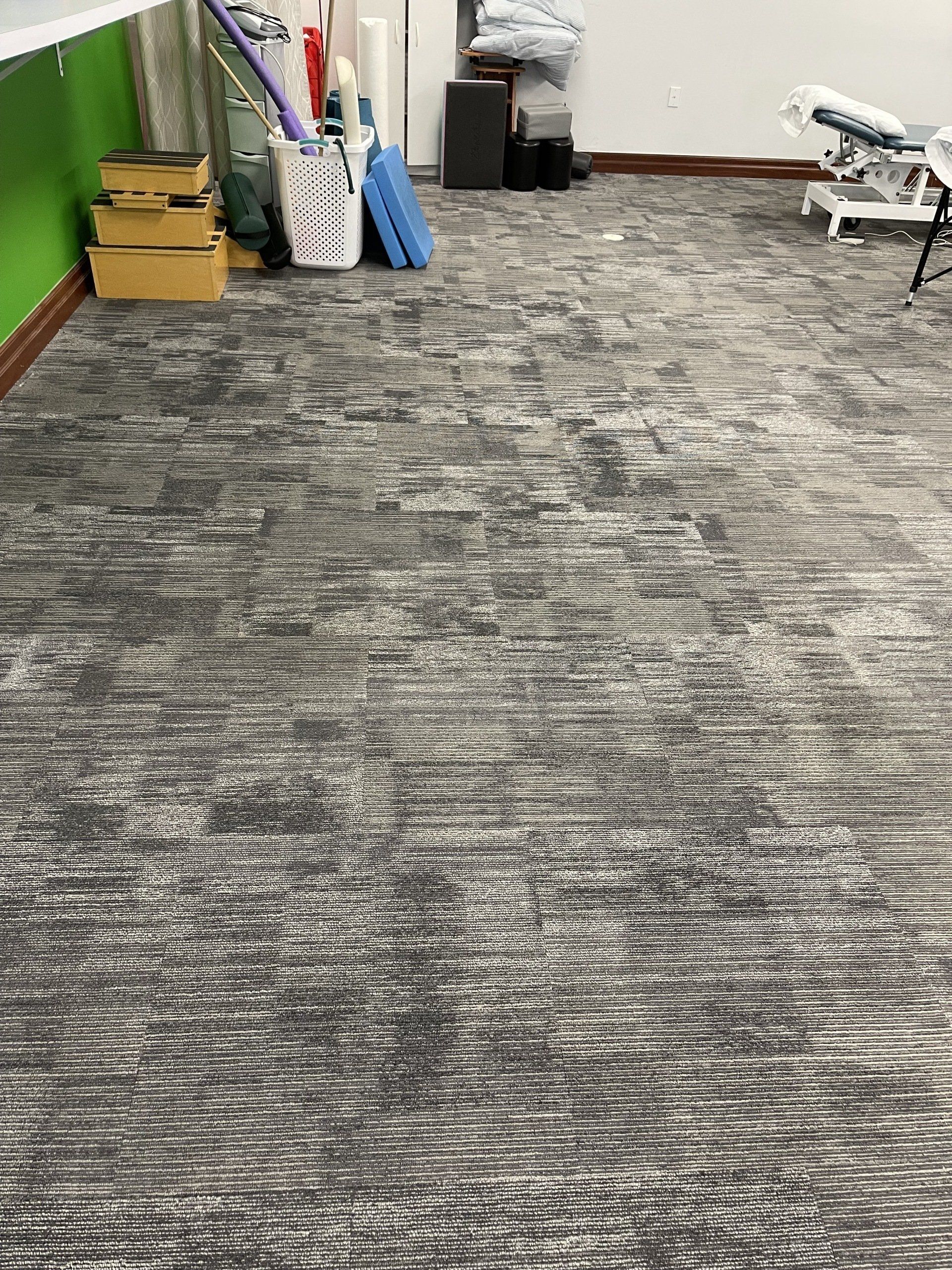 A gray carpeted floor in a room with a green wall.