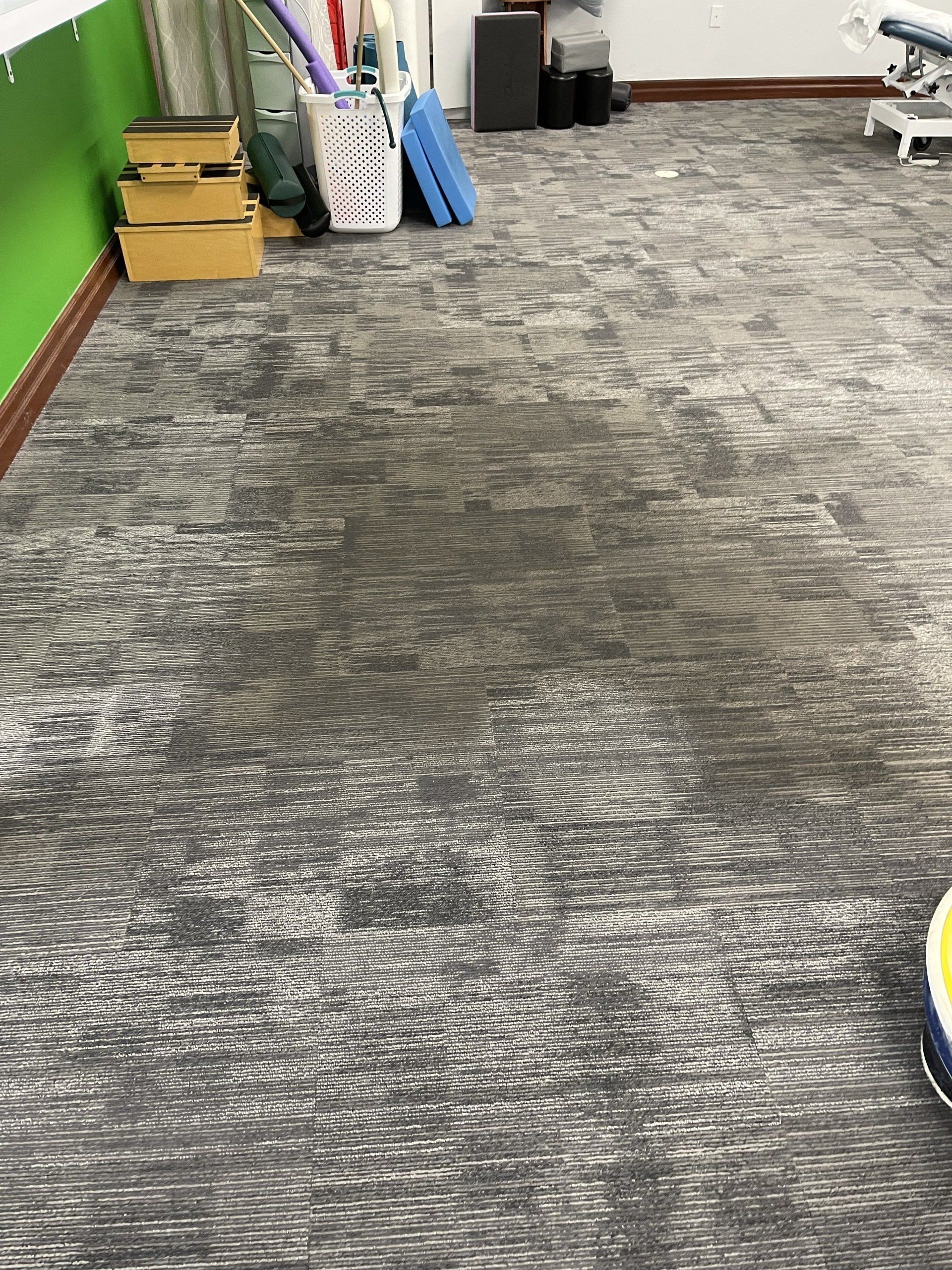 A dirty carpet in a room with a green wall.