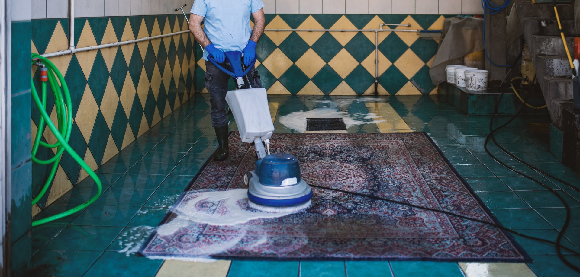 A man is cleaning a rug with a machine in a room.