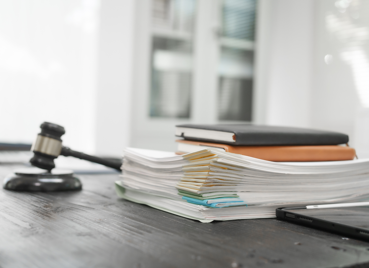 A judge 's gavel is sitting on a wooden table next to a stack of books.