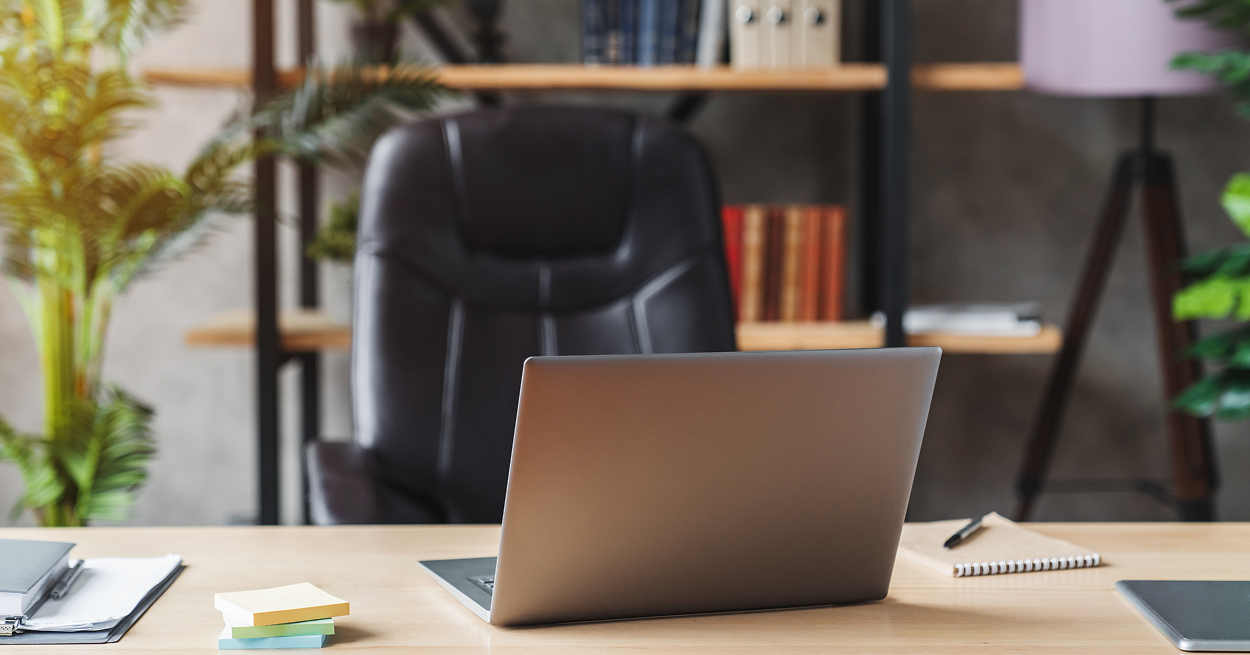 A laptop computer is sitting on a wooden desk in an office.