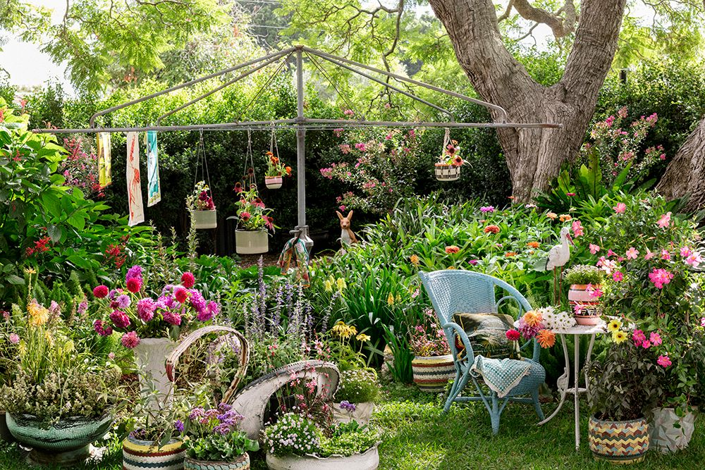 chairs in a garden with flowers in pots and  washing line behind